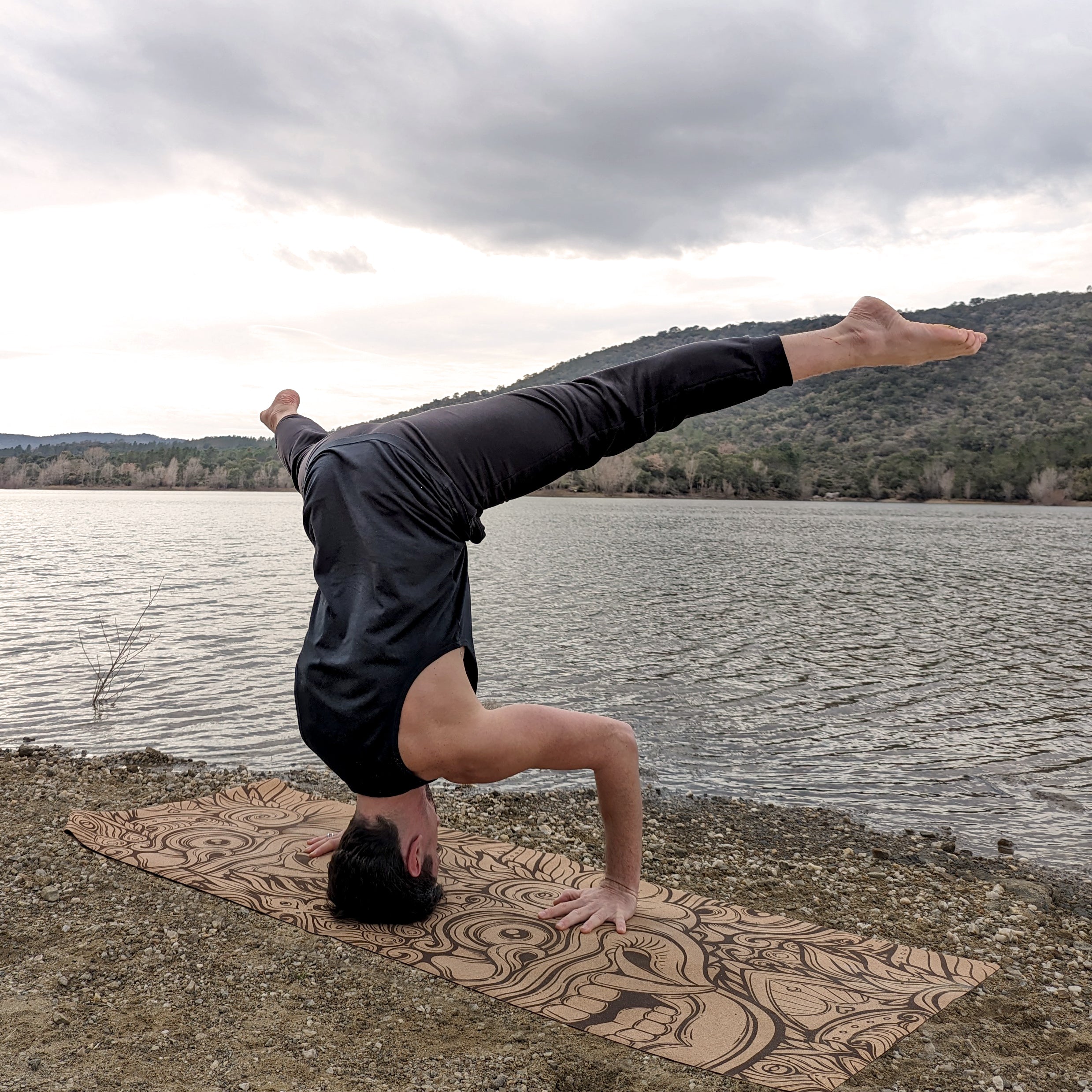 Yogi réalisant la posture du trépied (Sirṣāsana II) sur le tapis de yoga en liège Barong de ZenMotion. Ce tapis écologique, orné du Barong, tigre sacré balinais, incarne force, protection et harmonie. Conçu pour une pratique puissante et spirituelle, il offre une adhérence naturelle, une surface antibactérienne et une connexion à une tradition millénaire. Idéal pour Vinyasa, Hatha et Ashtanga, il célèbre l'équilibre, la bienveillance et la puissance intérieure. Un tapis confortable et inspirant pour une pr