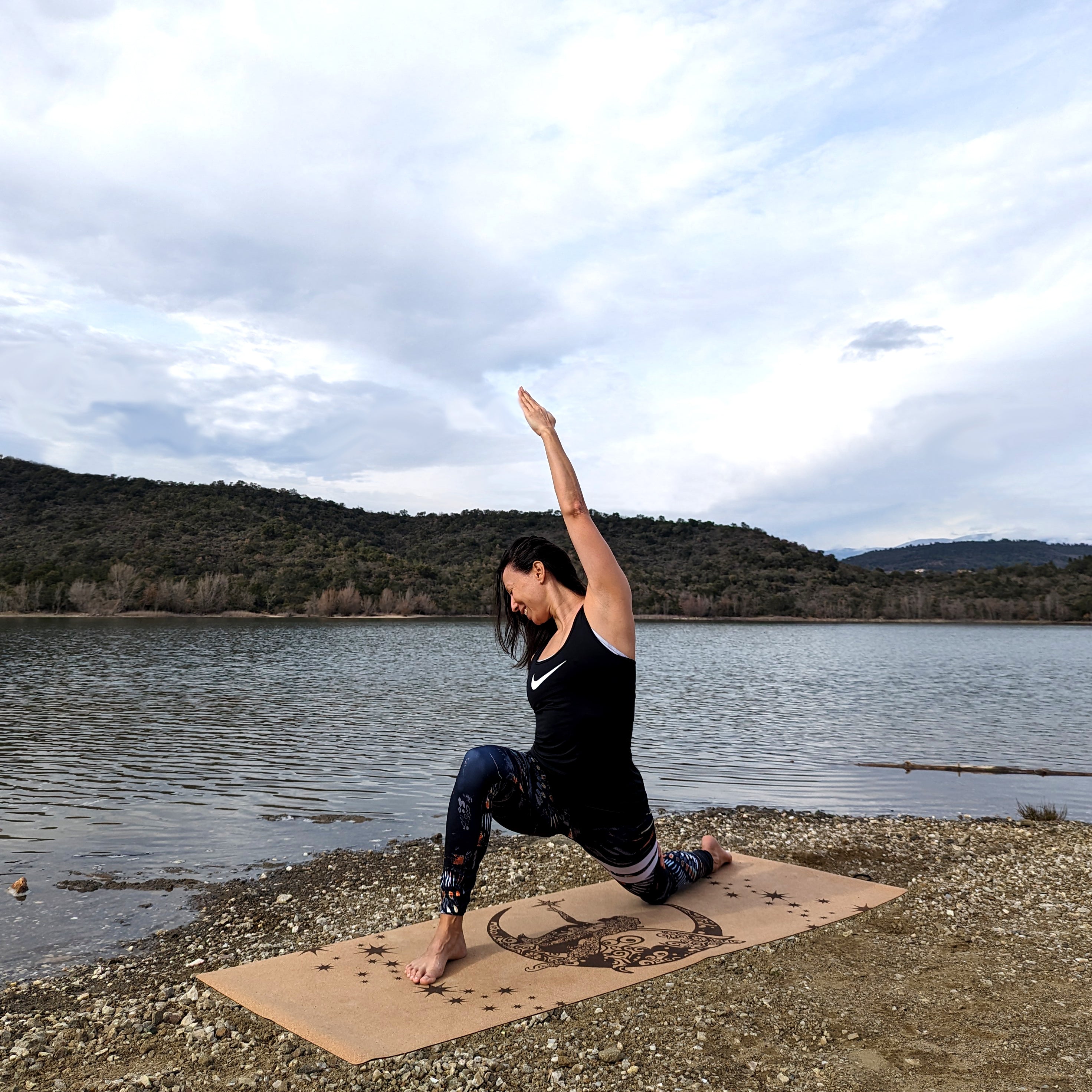 Femme réalisant la posture d'Anjaneyasana (fente basse) sur le tapis de yoga en liège Fairy Night de ZenMotion. Ce tapis écologique et poétique, orné d'une fée et d'étoiles scintillantes, incarne la magie, la transformation et l'intuition. Idéal pour une pratique enchanteuse, il apporte légèreté, joie et inspiration, parfait pour le Hatha, Vinyasa et la méditation. Un compagnon unique pour explorer votre voyage intérieur. Tapis de yoga confortable qui adhère