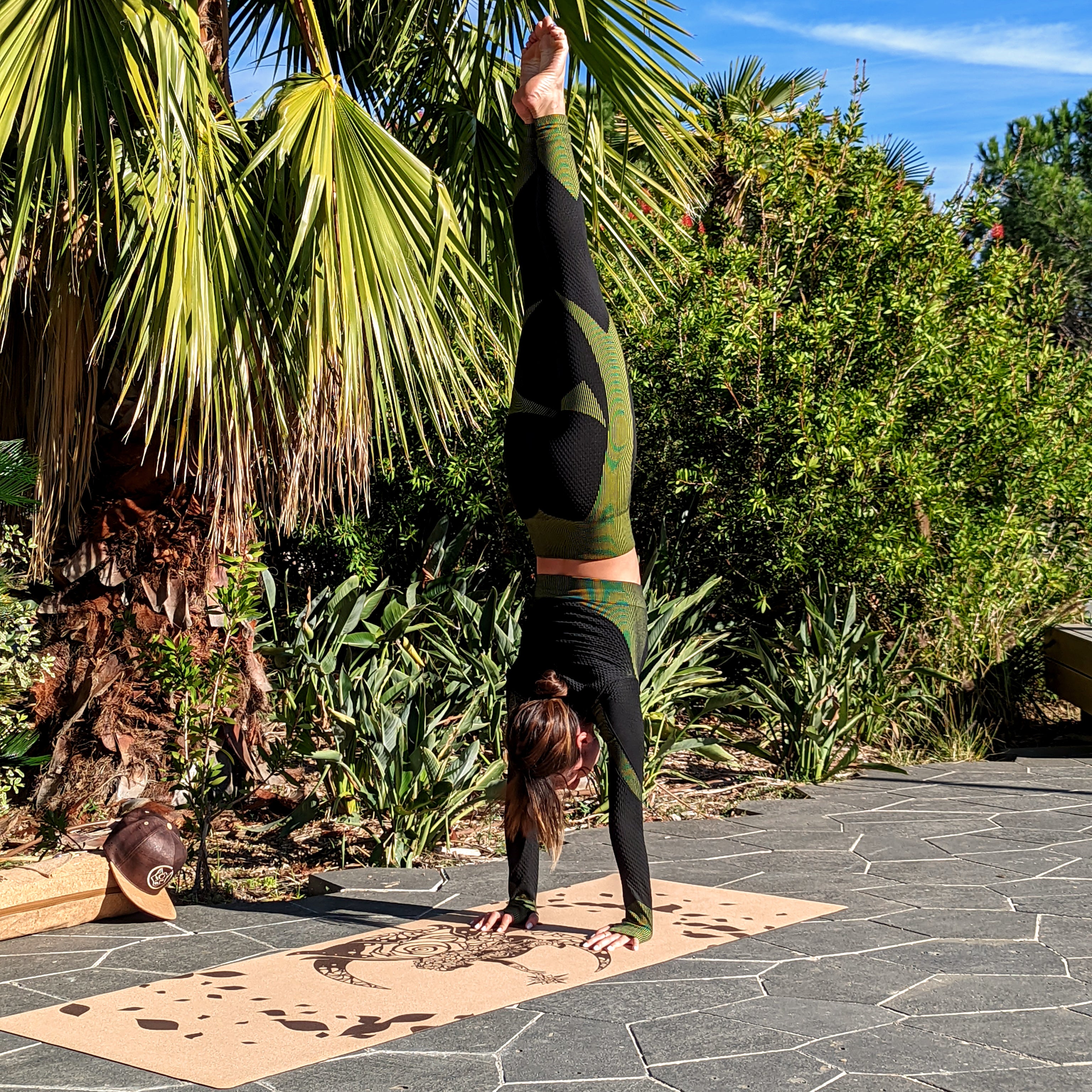 Yogini faisant un handstand sur le tapis de yoga en liège Fairy Tale de ZenMotion. Plongez dans un univers enchanté le tapis est capturé ici dans un champ bucolique sous un mimosa. Inspiré des fées, ce design délicat mêle motifs mandalas et une rose cachée, symbolisant légèreté, créativité et magie. Le liège naturel offre une adhérence ultime et un confort inégalé, parfait pour une pratique fluide de Hatha ou de Yin yoga. Éco-responsable et élégant, ce tapis transforme chaque séance.