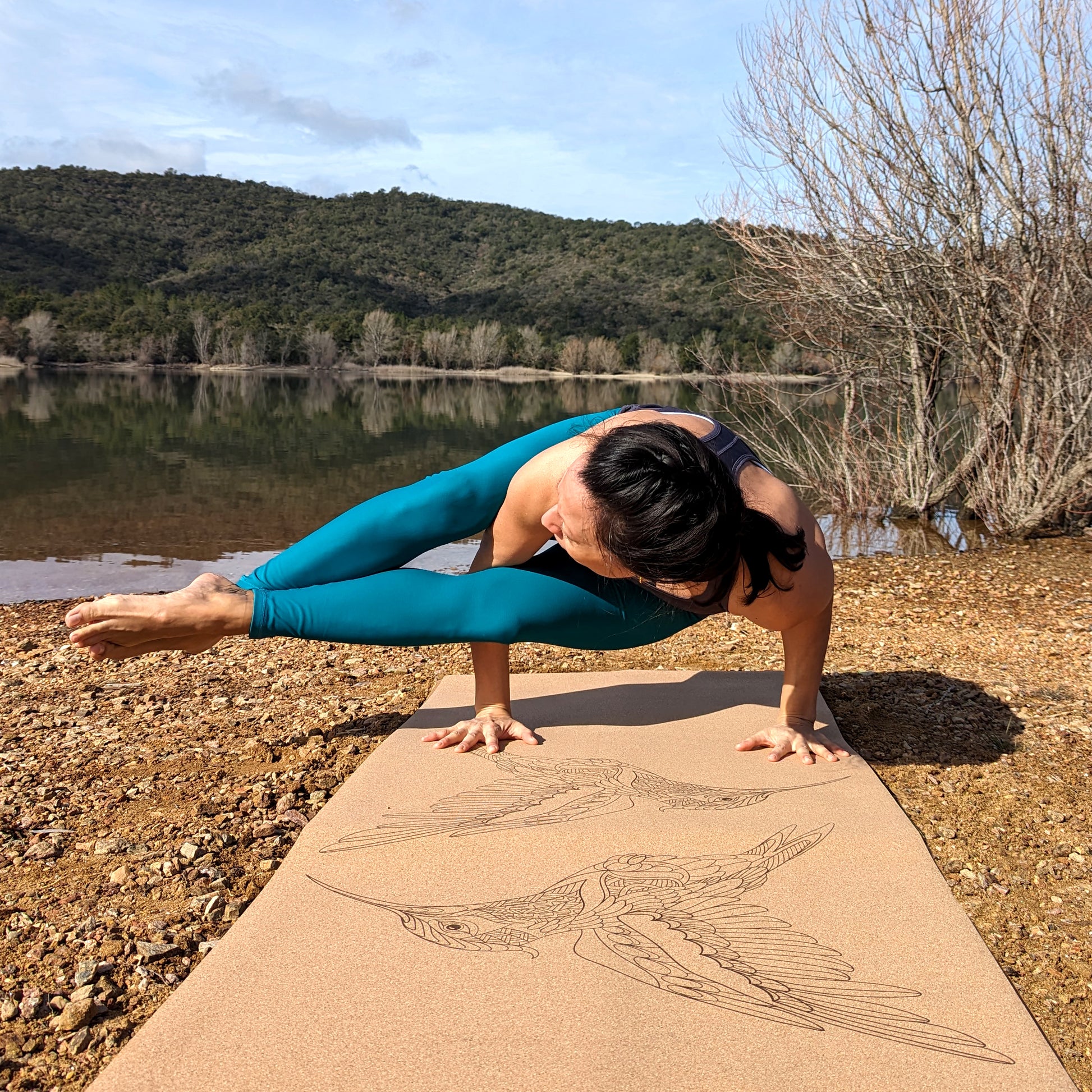 Femme réalisant la posture du corbeau sur le tapis de yoga en liège Flying Jewels de ZenMotion. Ce tapis écologique, au design épuré et symétrique, représente deux colibris en miroir, symboles de joie, résilience et harmonie. Idéal pour une pratique spirituelle, il offre une surface qui adhère, douce, stable et naturelle, favorisant concentration, légèreté et grâce dans chaque mouvement. Parfait pour le Hatha, Vinyasa et la méditation.