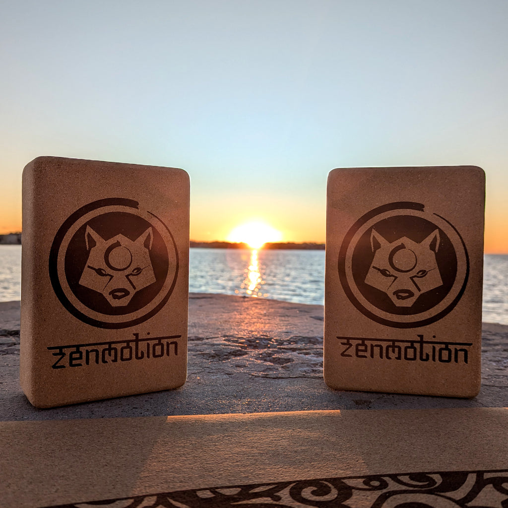 Deux briques de yoga ZenMotion posées sur un tapis en liège, avec un lever de soleil en bord de mer en arrière-plan. Accessoires écologiques et naturels, parfaits pour améliorer l'alignement, la souplesse et la stabilité lors de vos pratiques de Hatha, Vinyasa ou méditation. Une scène apaisante, symbolisant harmonie, énergie positive et connexion mindful avec la nature.
