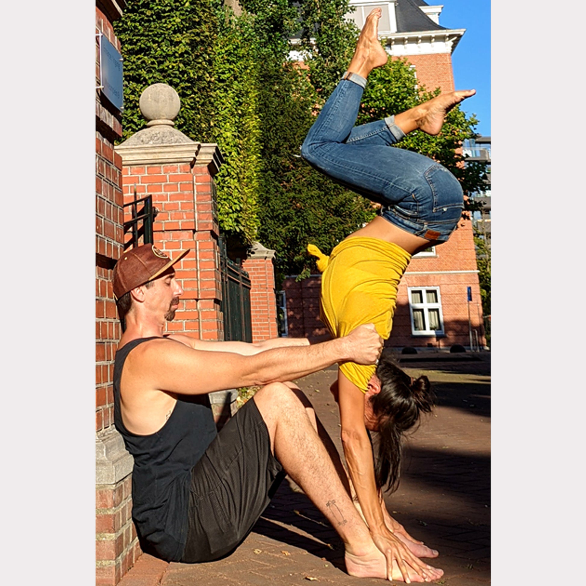 Un couple faisant de l'acroyoga. L'homme porte une casquette en liège ZenMotion, un accessoire élégant et écologique conçu pour les amateurs de style et de confort. Fabriquée en cuir de liège durable, cette casquette offre une texture lisse, une résistance aux taches et une isolation thermique optimale, parfaite pour protéger du soleil lors de vos séances de yoga en extérieur ou de vos aventures estivales. Alliant esthétique et praticité.